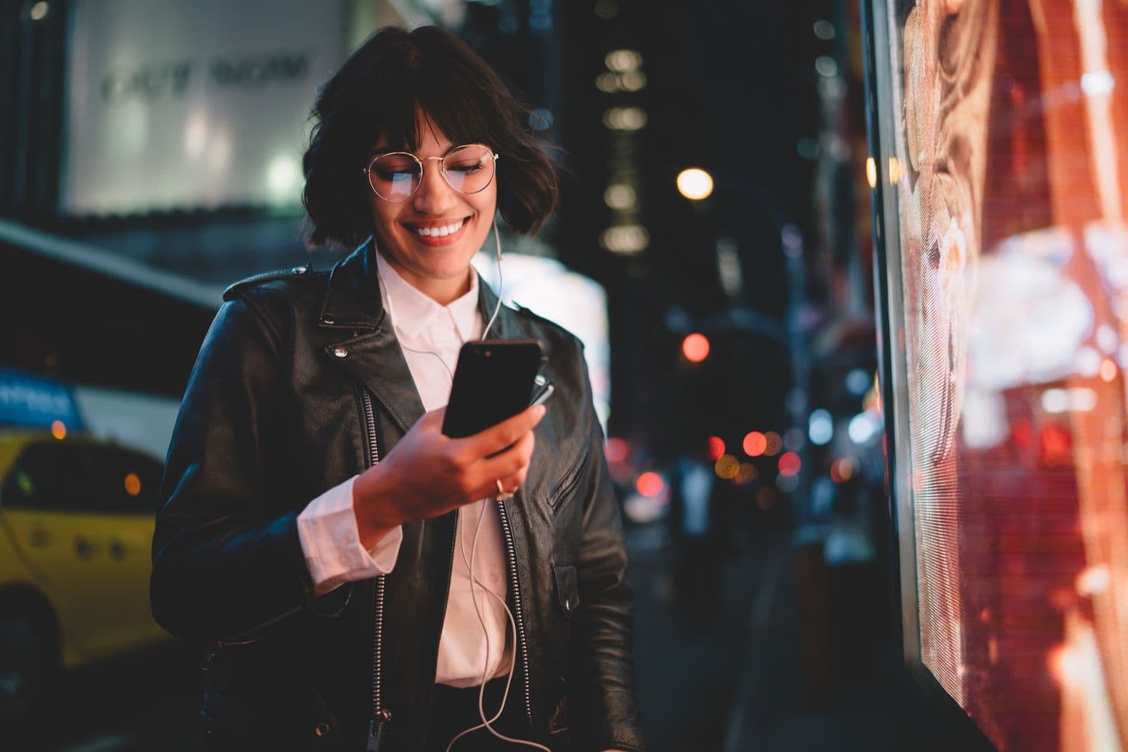 Professional checking a phone beside a digital display at night