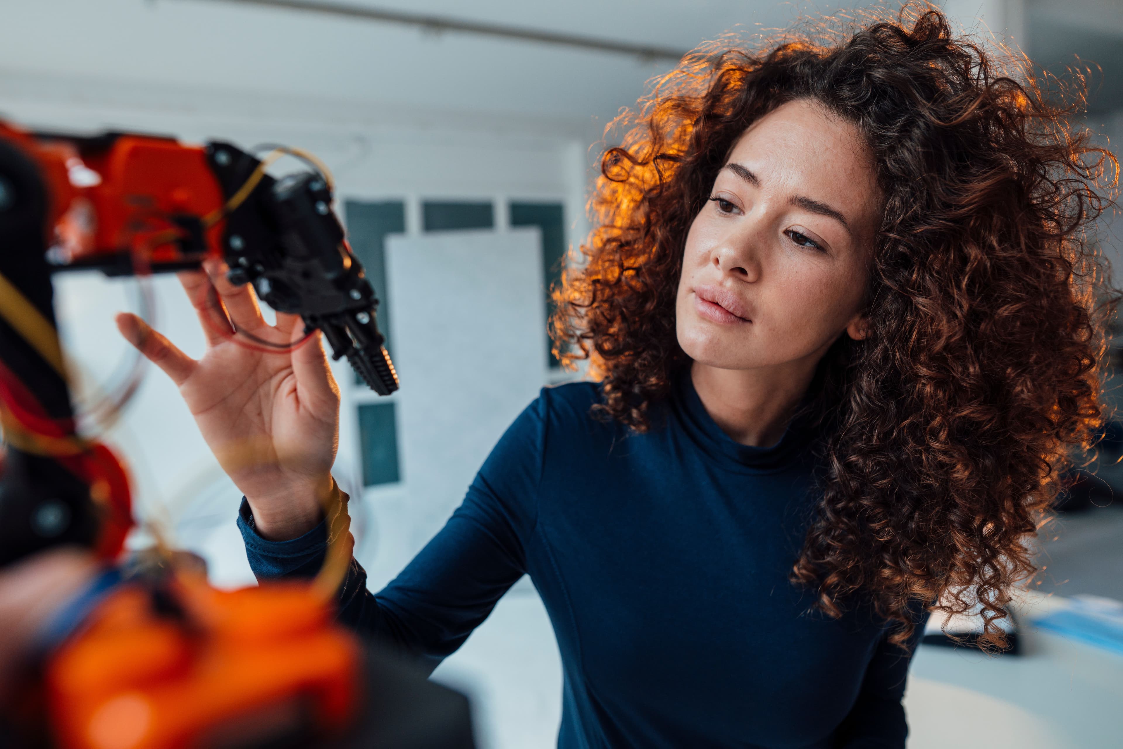Specialist closely inspecting a robotic arm, absorbed in skilled technical work.