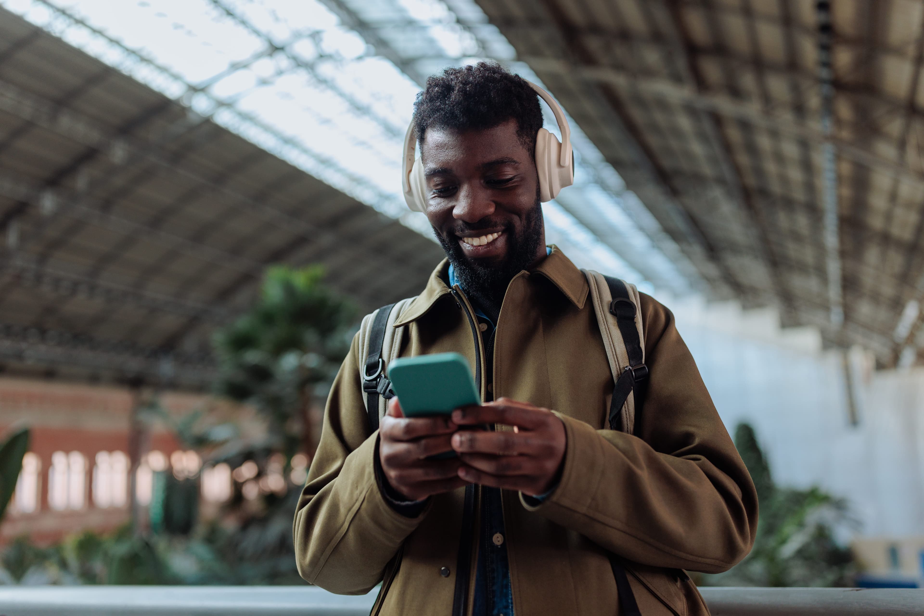 Professional wearing headphones checking a phone in a station