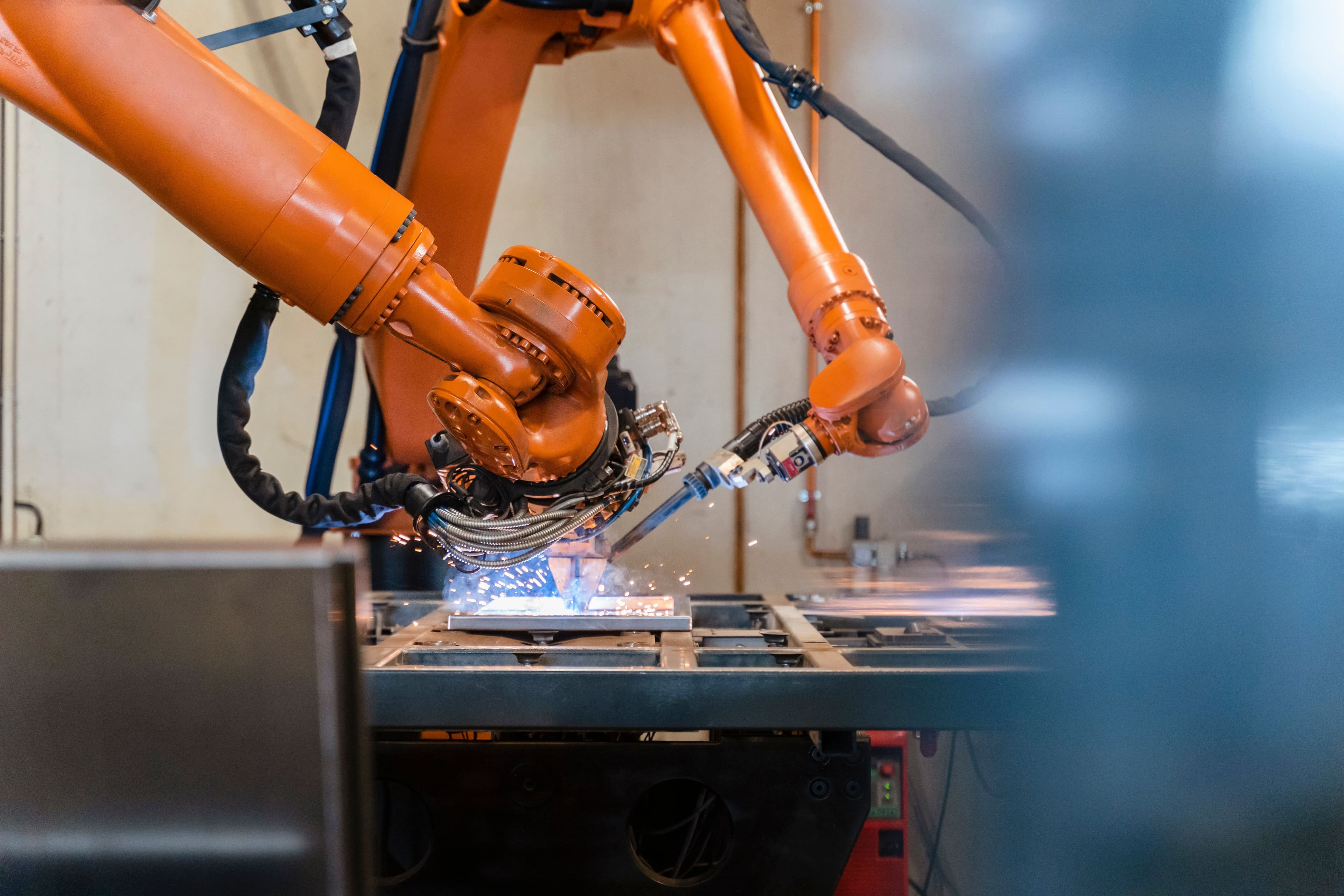 robotic welding arm with visible sparks in an industrial setting